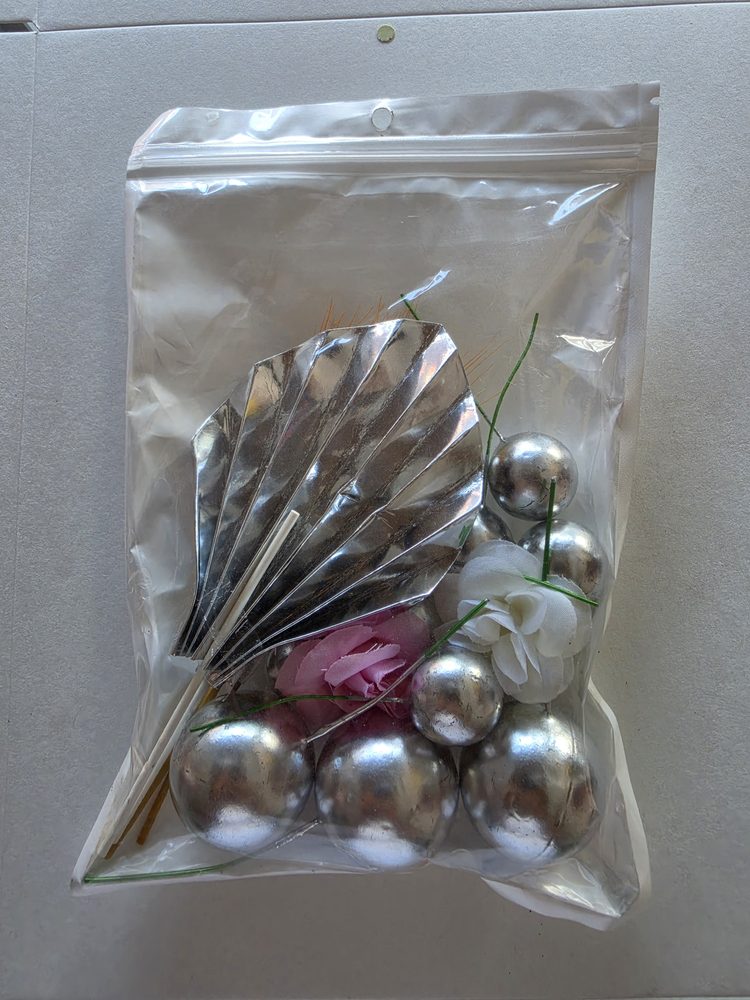 Bolsa con esferas plateadas con alambre, un abanico plateado y flores
