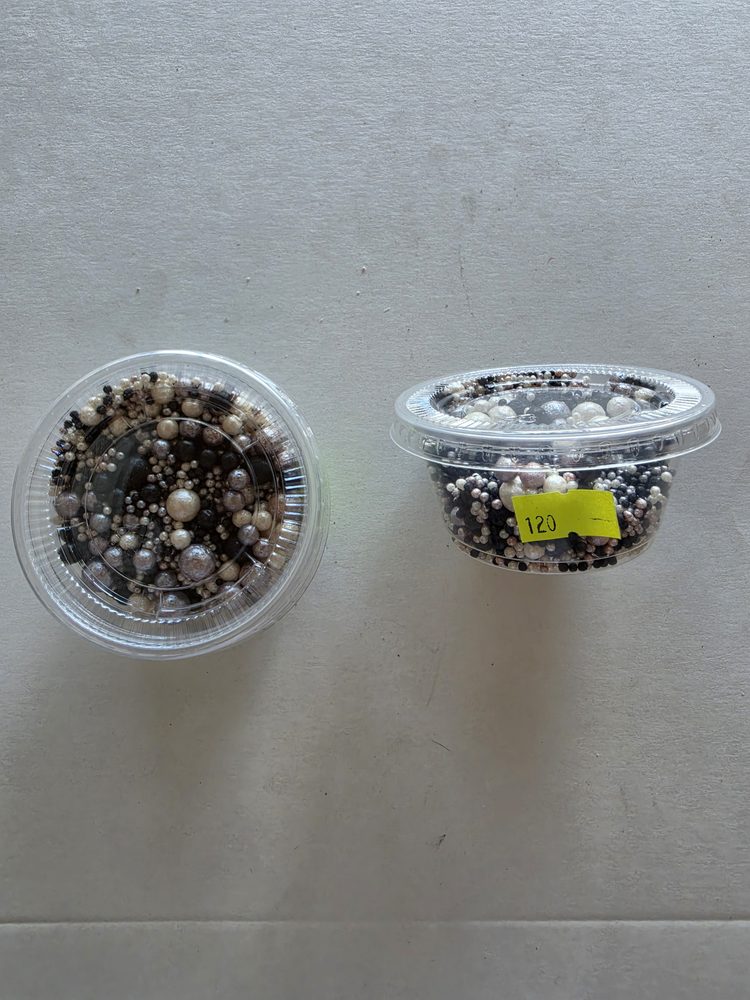 Mezcla de perlas y grageas blancas, negras y plateadas en dos vasitos
