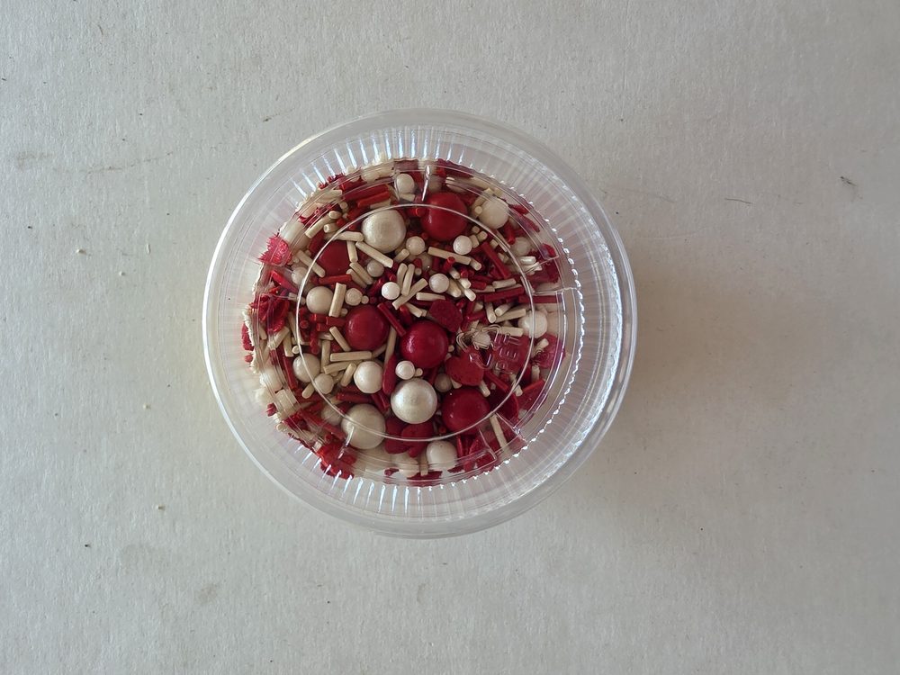 Envase plástico con mezcla de sprinkles y perlas comestibles en rojo