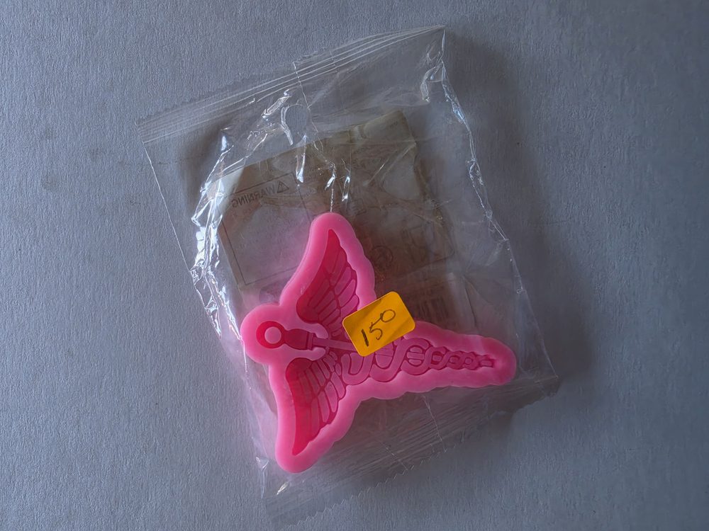Molde de silicón rosado con figura de caduceo con alas (simbolo