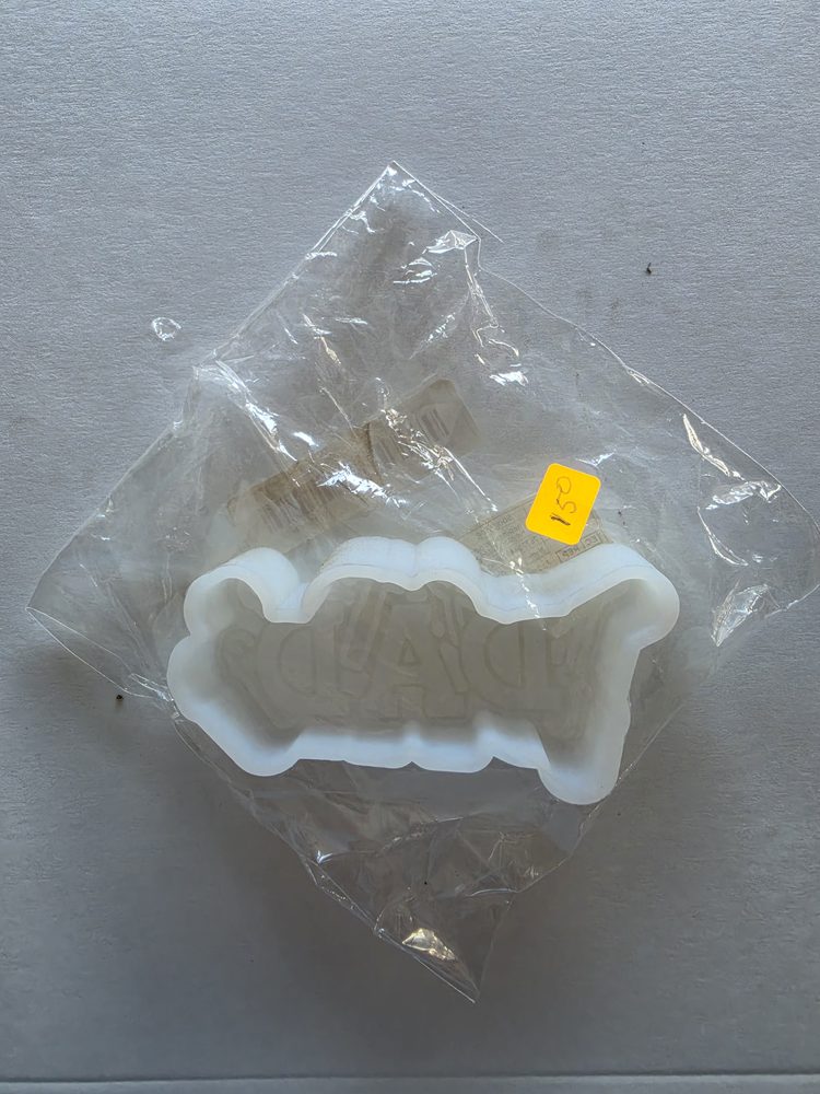 Molde de silicón blanco con letrero en relieve que dice DAD