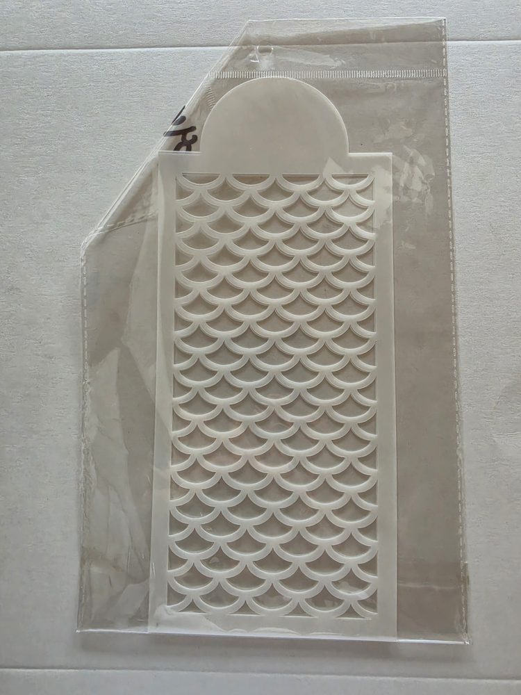 Esténcil de plástico blanco con patrón calado de escamas de sirena